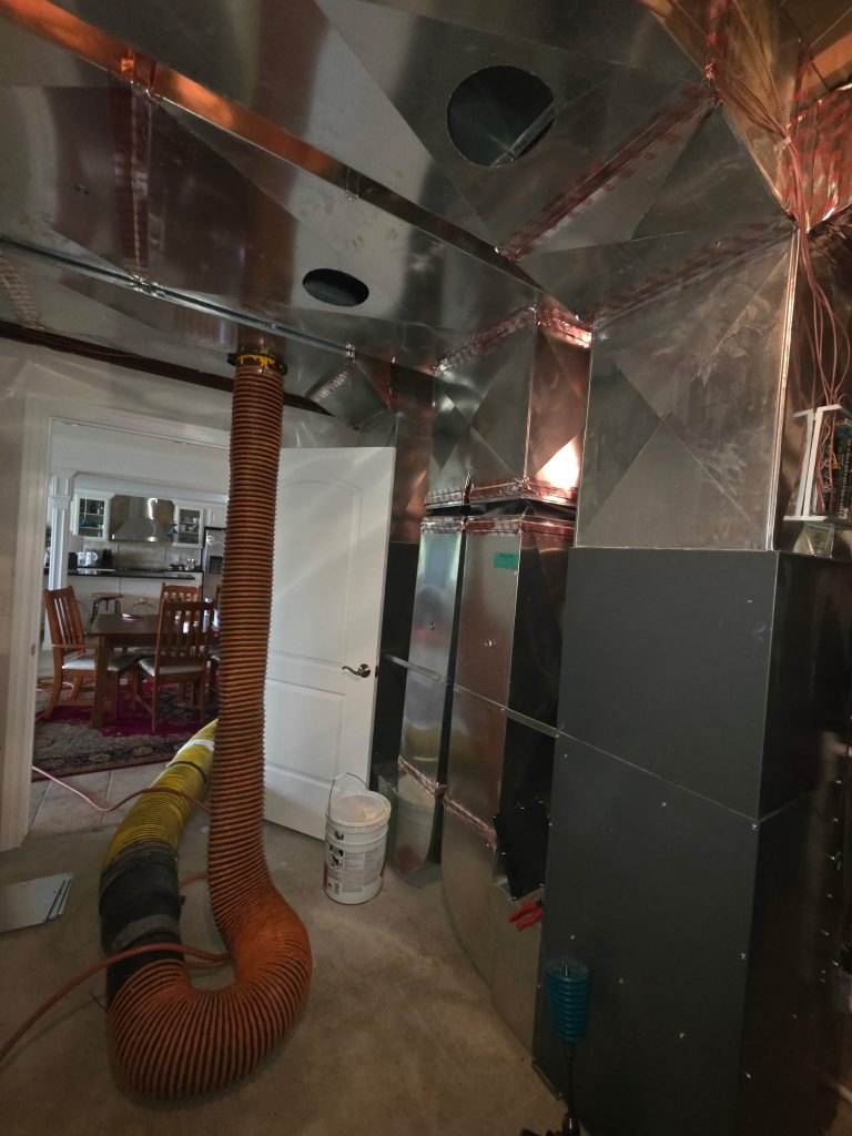 Truck-mounted vacuum hose connected to the main trunk line during HVAC cleaning in Troy, MI